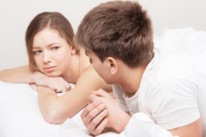 Young woman worried in bed with partner: SBDMedical Women’s Issues Blog
