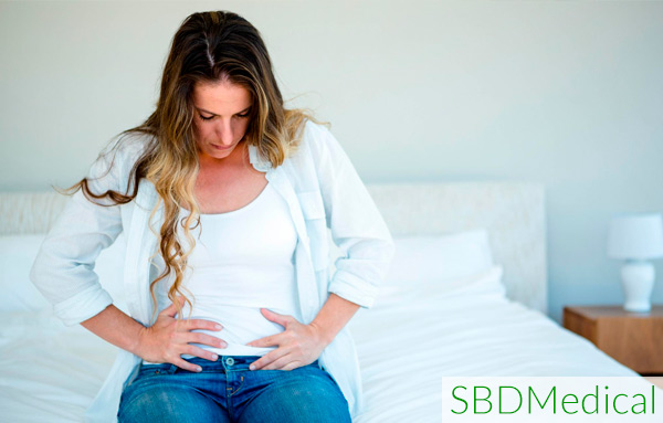 woman sitting on bed holding her stomach from heavy period pain